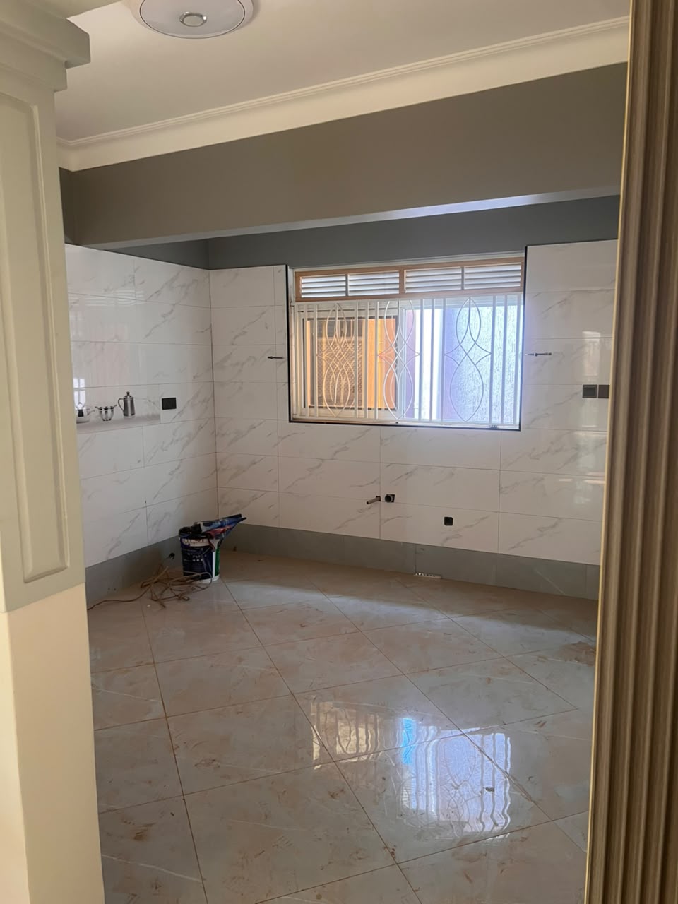 BEFORE: the empty kitchen with tiled walls, floor and window but no cabinets